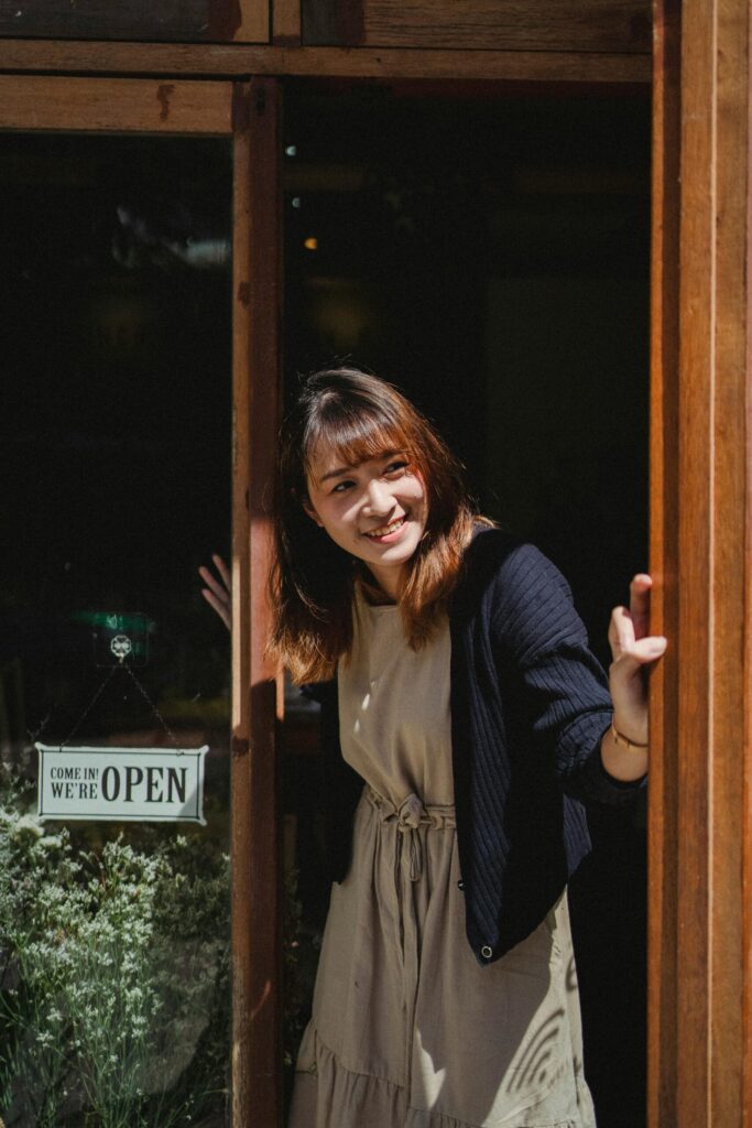 A woman opens the door of her shop.