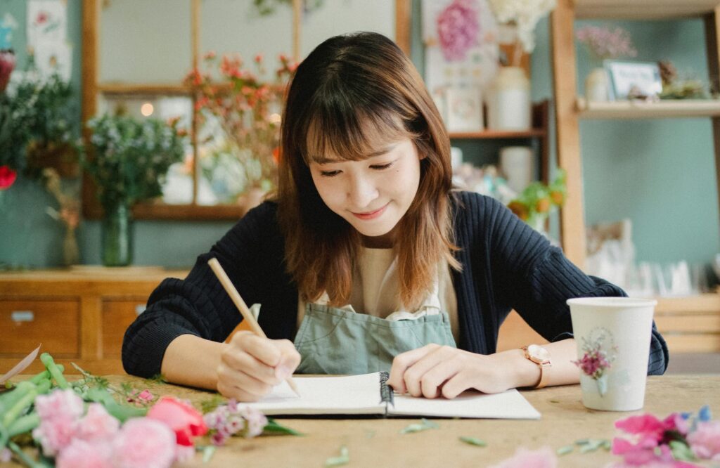 A woman business owner writes on her ledger.