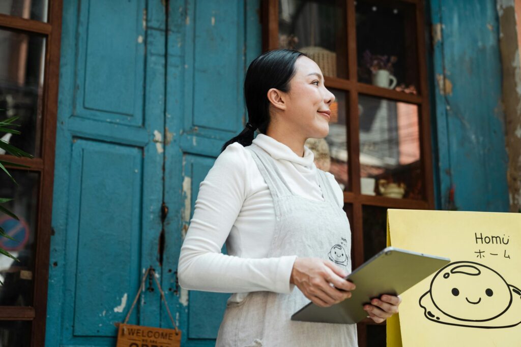 Woman with apron waits for her deliveries in front of her shop