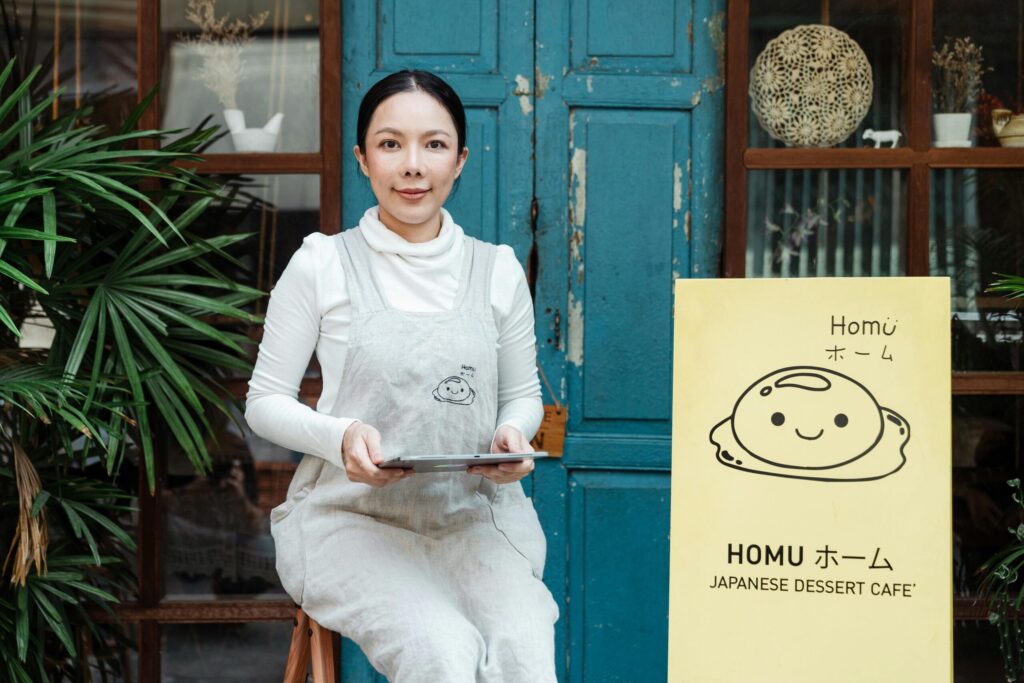 A woman with white apron waits for customers at the store front. 